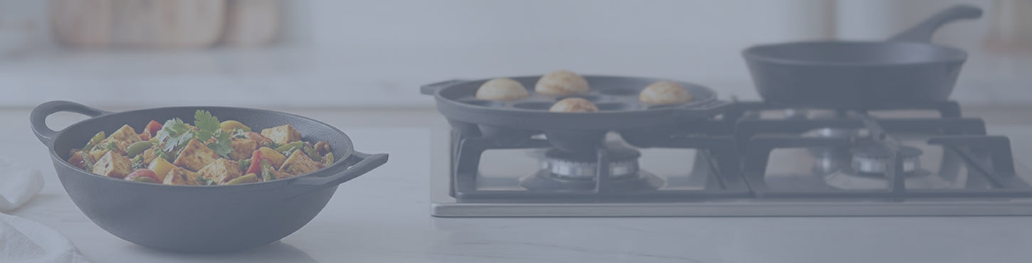 Cast iron cookware set with frying pans and serving bowl displayed in a modern kitchen